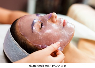 The beautician applies a transparent jelly peer mask to the girl's face. Facial skin care.  - Shutterstock ID 1907041546