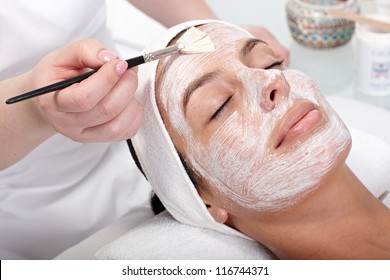 Beautician applying cream by brush on woman's face. - Shutterstock ID 116744371