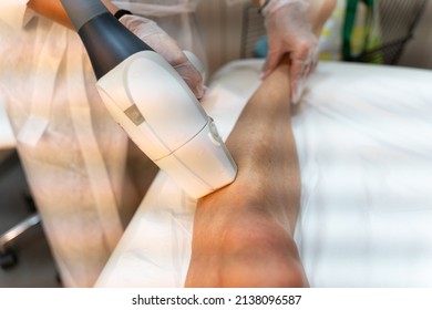 Beautician Applying Laser Hair Removal Gun On Leg Of Man. Beauty Treatment Concept