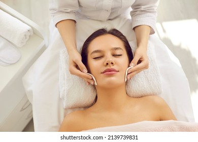 Beautician at beauty center removing makeup with cotton discs, cleaning skin before facial massage or rejuvenating detox mask, applying lotion or chemical peel for beautiful perfect bright complexion - Shutterstock ID 2139739831