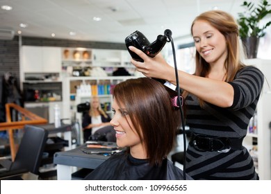 Beautician blow drying woman's hair after giving a new haircut at parlor