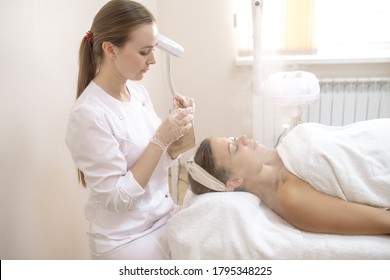 The Beautician Cleans The Patient's Face By Steaming The Pores Of The Skin With Steam
