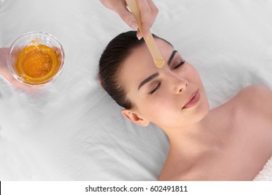 Beautician Depilating Young Woman's Face With Wax In Spa Center