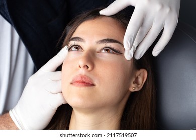 Beautician doctor hands in gloves touching female face. Upper eyelid reduction, double eye lid removal plastic surgery concept. 