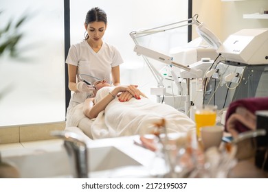 Beautician doing cosmetology procedures using radio frequency beauty machine for skin care in modern beauty salon. - Shutterstock ID 2172195037