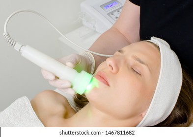 Beautician Doing Green Led Light Therapy To Female Customer In Beauty Salon, Facial Photo Therapy For Skin Pore Cleansing. Anti-aging Treatments And Photo Rejuvenation Procedure