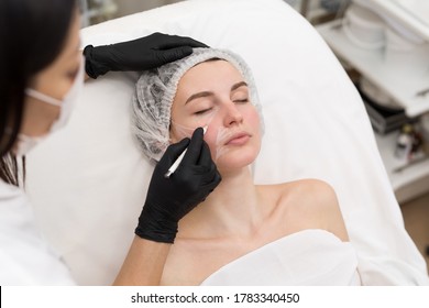 Beautician draws the contours of a white pencil on the face of the patient. Schematic marking before contouring. Close-up preparation of the face for cosmetic plastic surgery - Powered by Shutterstock