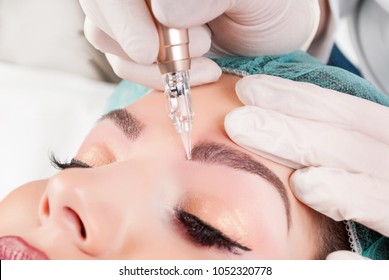 Beautician Hands Doing Eyebrow Tattoo On Woman Face.Permanent Brow Makeup In Beauty Salon. Closeup Of Specialist Doing Eyebrow Tattooing For Female. Cosmetology Microblading Treatment