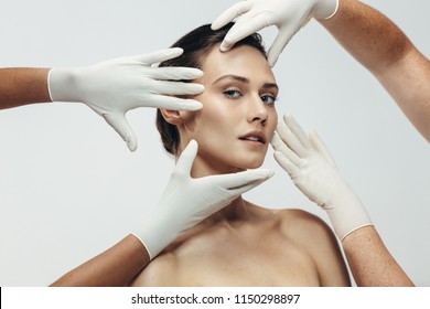 Beautician hands in gloves checking female face skin before aesthetic medical therapy. Woman going under cosmetic treatment on her facial skin.