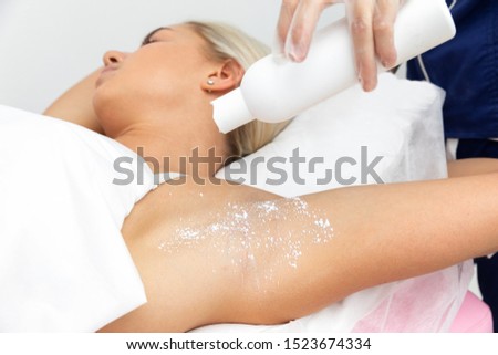 beautician makes depilation underarms of the client lying on a pink couch in a beauty salon. beautician pour talcum powder from the bottle. slow motion