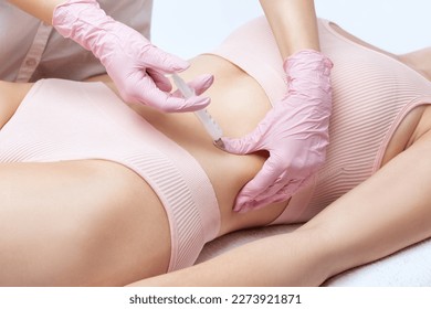 beautician makes lipolytic injections to burn fat on woman's belly and waist. Women's aesthetic cosmetology in a beauty salon. The concept of cosmetology.