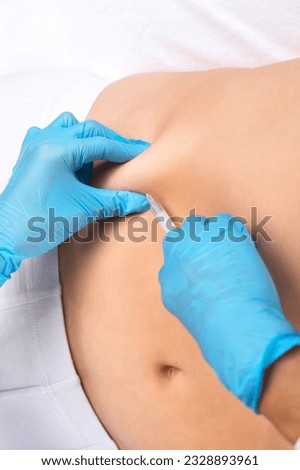 A beautician makes lipolytic injections to burn fat on a man's belly. Male aesthetic cosmetology in a beauty salon.