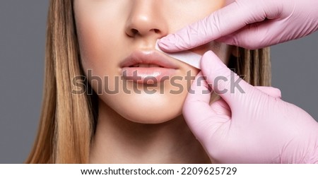 The beautician makes a mustache removal with wax in a young woman. hair removal procedure on a woman’s body.