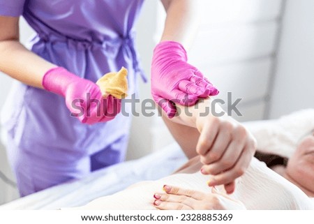 A beautician makes a sugar paste depilation of a woman's hand in a beauty salon. Female cosmetology. Removing unnecessary hair on the hand.  Sugar depilation. Depilatory sugar paste