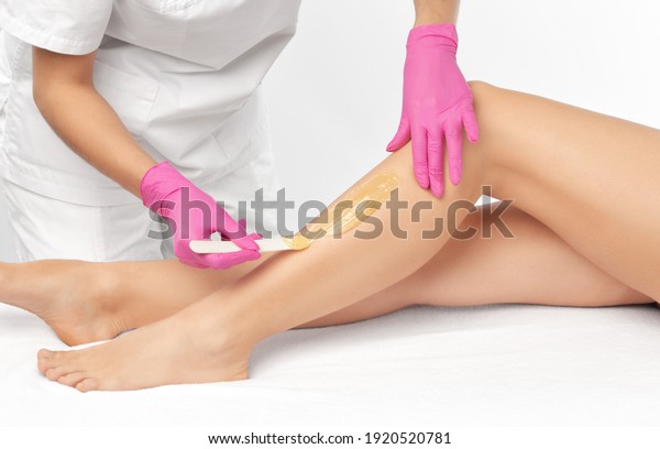 A beautician\
makes a sugar paste depilation of a woman\'s legs in a beauty salon.\
Female aesthetic cosmetology.