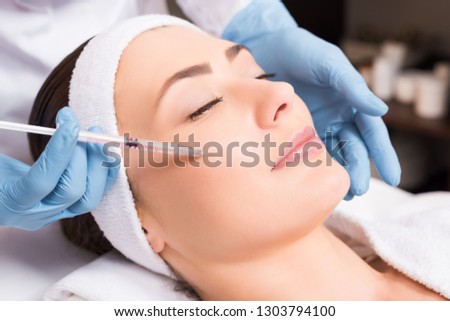 beautician making injection face attractive woman at beauty salon