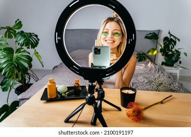 Beautician making make up tutorial on mobile phone at home. Female is applying facial sheet mask or cream. Cosmetic procedures, mask for skin care, woman young, spa salon.