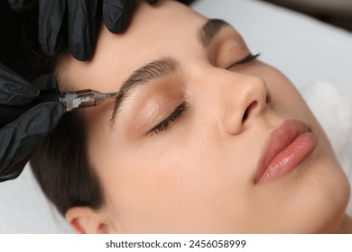 Beautician making permanent eyebrow makeup to young woman, closeup - Powered by Shutterstock