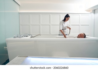 Beautician performing hydromassage procedure in spa salon