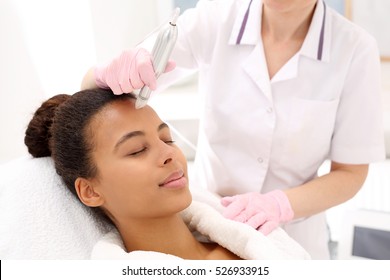 Beautician performs a needle mesotherapy treatment on a woman's face 