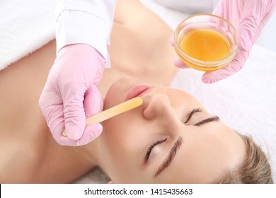 Beautician Removing Hair Above Upper Lip Of Young Woman In Salon