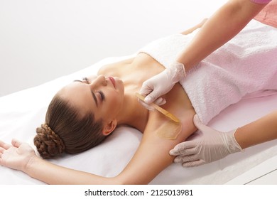 Beautician is removing hair from young female armpits with hot wax. Woman has a beauty treament procedure. Depilation, epilation, skin and health care concepts. - Shutterstock ID 2125013981
