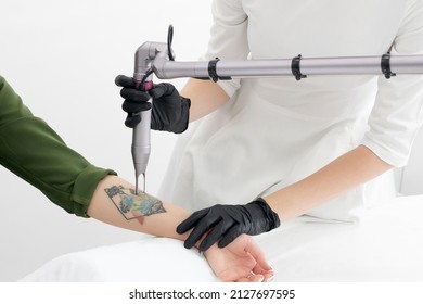 Beautician Using Laser Device To Remove An Unwanted Tattoo From Female Arm. Concept Of Erasing Tattoos As An Expensive Procedure In A Cosmetology Clinic