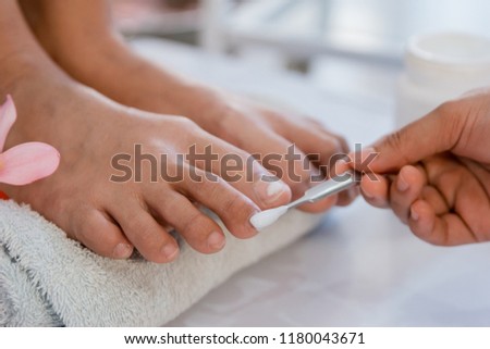 Beautician using a nail polish giving a customer pedicure