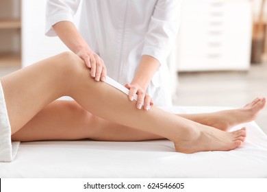 Beautician Waxing Female Legs In Spa Center