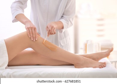 Beautician Waxing Female Legs In Spa Center