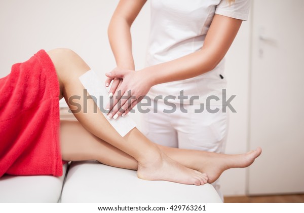 Beautician\
waxing woman a leg at salon /\
Depilation.
