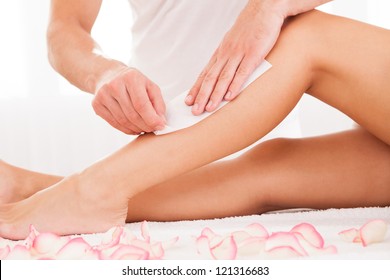 Beautician Waxing A Woman's Leg Applying A Strip Of Material Over The Hot Wax To Remove The Hairs When Pulled