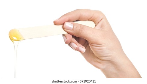 Beauticians Hand With Green Glove Holding A Roll On Liposoluble Wax Cartridges From Honey For Waxing Wooden Spatulas For Wax On Black. Preparing For Epilation