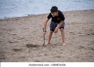 Beautiful 10 Year Old Boy On The Beach Playing With A Stick