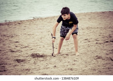 Beautiful 10 Year Old Boy On The Beach Playing With A Stick