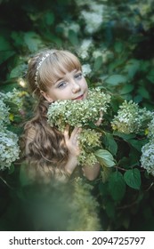 Beautiful 11-year-old Girl With Long Blonde Hair In Hydrangea Flowers. Image Of A Charming Little Princess.