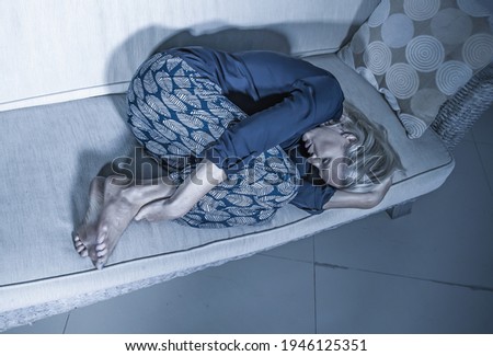 beautiful 40s woman depressed at home - dramatic portrait of sad and desperate blonde girl on couch suffering depression problem and anxiety crisis feeling helpless and lonely