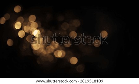 A beautiful abstract background featuring soft, glowing golden bokeh lights scattered across a dark, black backdrop.