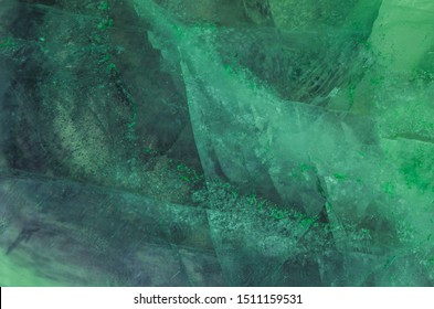 The beautiful abstract mysterious colorful green blue and purple texture of the crystal of quartz fluorite mineral with cracked and mosaic ice structure with fluorescent light.