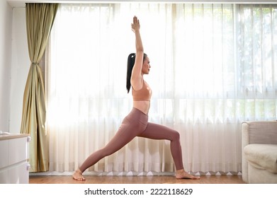 Beautiful and active fit Asian woman in sportswear practicing yoga at home, practicing High Lunge pose or warrior I pose. side view - Shutterstock ID 2222118629