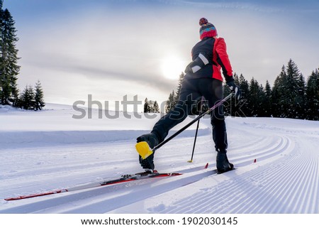 beautiful active senior woman cross-country skiing in fresh fallen powder snow in the Allgau alps near Immenstadt, Bavaria, Germany