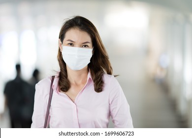 Beautiful adult middle age Asian working office businesswoman wearing surgical protective medical mask on face looking straight to camera while walking in path way to work in office. Health care idea. - Powered by Shutterstock