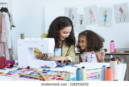 Beautiful Adult Mother Teaching, Bonding Her Mixed Race African Little Cute Daughter Girl Using Sewing Machine For Making Dress, Clothes At Home Or Tailor Shop, Smiling With Happiness Together