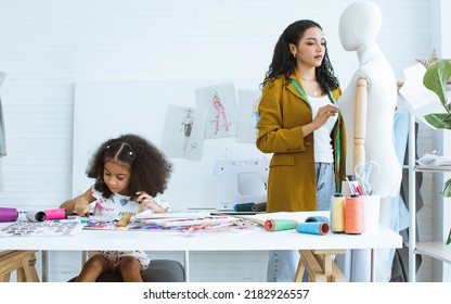 Beautiful Adult Mother Teaching, Bonding Her Mixed Race African Little Cute Daughter Girl Using Sewing Machine For Making Dress, Clothes At Home Or Tailor Shop, Smiling With Happiness Together