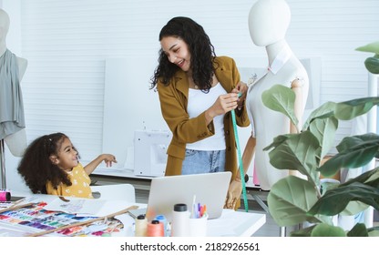 Beautiful Adult Mother Teaching, Bonding Her Mixed Race African Little Cute Daughter Girl Using Sewing Machine For Making Dress, Clothes At Home Or Tailor Shop, Smiling With Happiness Together