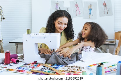 Beautiful Adult Mother Teaching, Bonding Her Mixed Race African Little Cute Daughter Girl Using Sewing Machine For Making Dress, Clothes At Home Or Tailor Shop, Smiling With Happiness Together