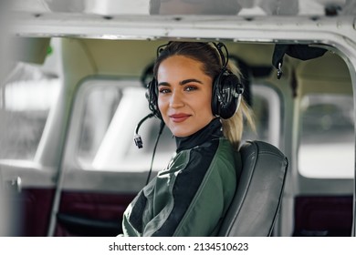 Beautiful adult woman, comfortably sitting in the cockpit, looking at the camera.