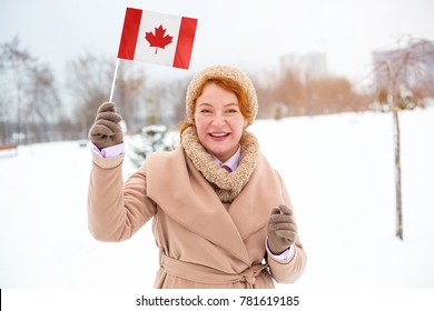 Beautiful Adult Woman Holding A Flag Of Canada Standing In The Background Of A Winter Landscape.