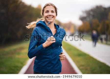 Beautiful adult woman is jogging outdoor on cloudy day in autumn.