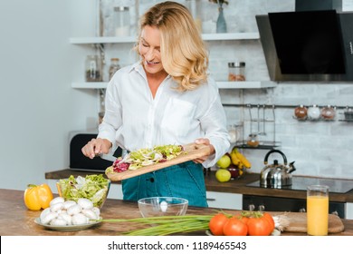beautiful adult woman making healthy salad at kitchen
